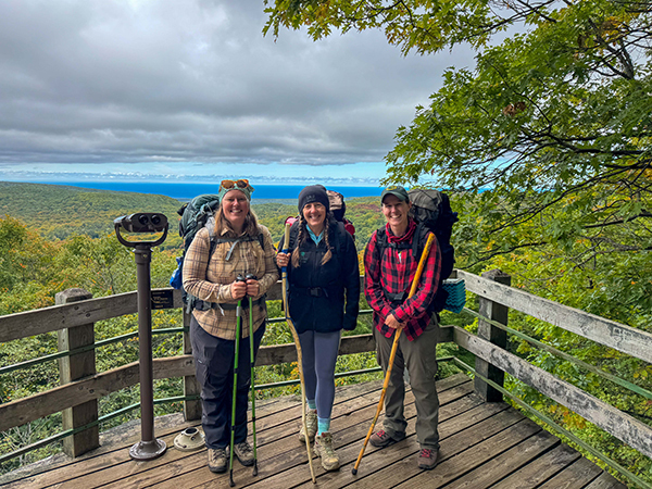 Three women stand on a viewing deck at Summit Peak in the Porcupine Mountains.