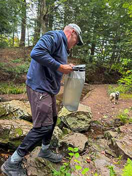A man retrieves water on a backcountry hike.