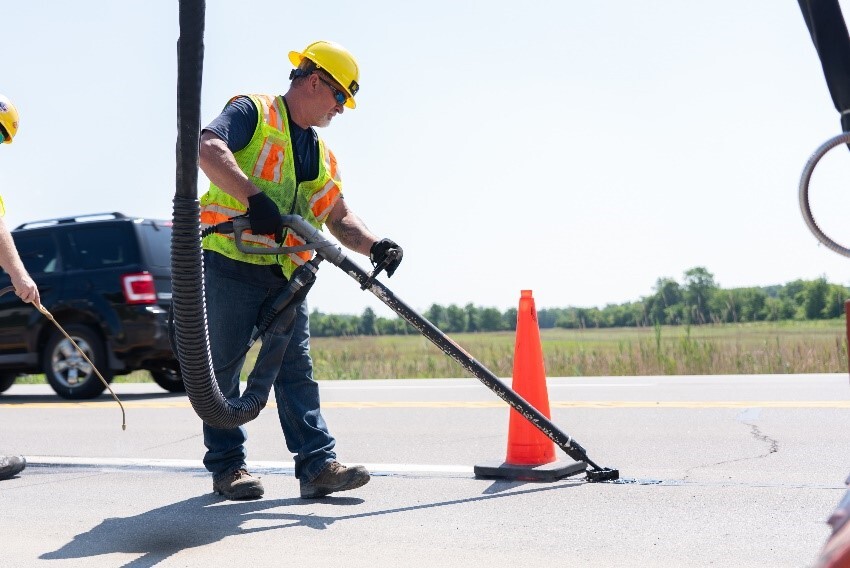Construction worker patching cracks in the pavement