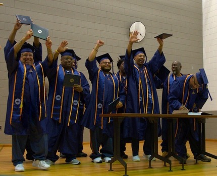 College graduates celebrating by waving their hands and degrees in the air