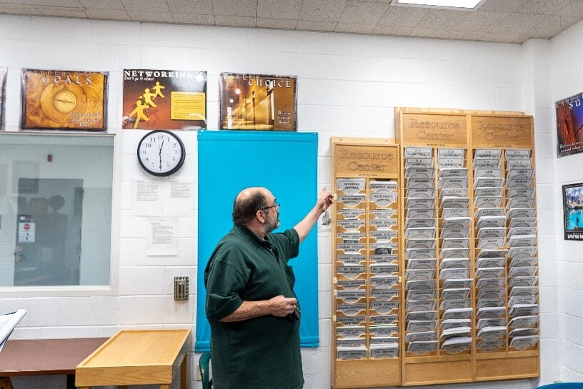 Man pointing to a wall of various publications.