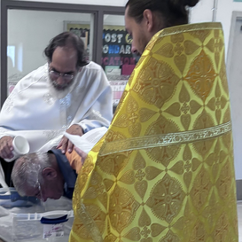 A prisoner is baptized by two Orthodox priests