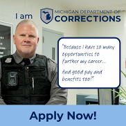 A corrections officer stands behind a desk