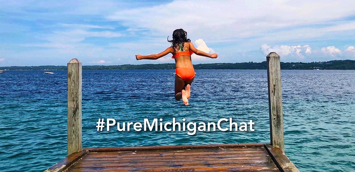 A girl jumps off a dock into the blue waters of Lake Michigan.