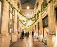 An indoor shopping alley decorated with holiday garland. 