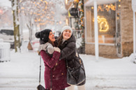 Two woman hugging outside a store in downtown Traverse City during winter. 