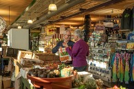 A man and woman shopping at an indoor farmer's market.