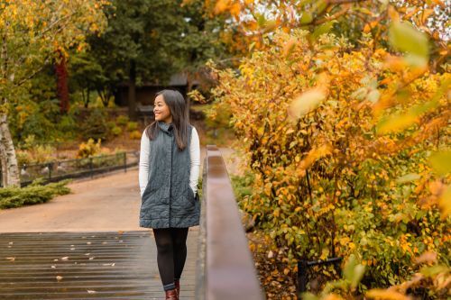 A woman walking on a foot bridge by a fall tree. 