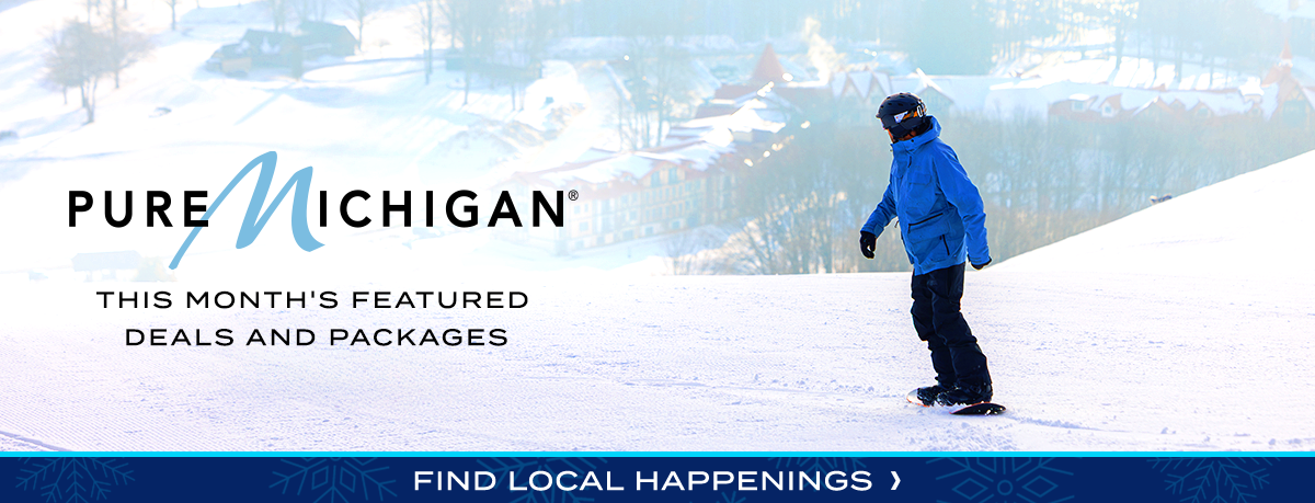 A snowboarder on a ski run above a ski resort. 