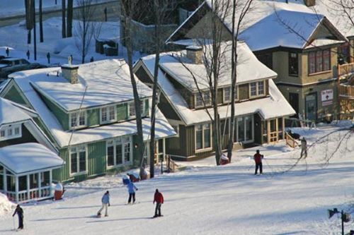 Skier and snowboarders riding past lodges at Crystal Mountain.