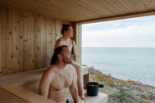 A man and woman in a sauna with a window overlooking Lake Superior. 