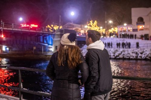 A couple standing beside a river at night during winter.