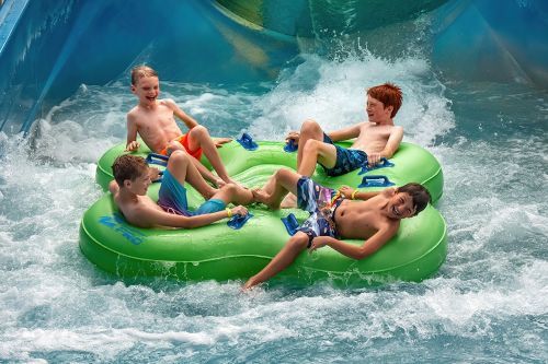Four children on a group innertube exiting an indoor waterslide.  