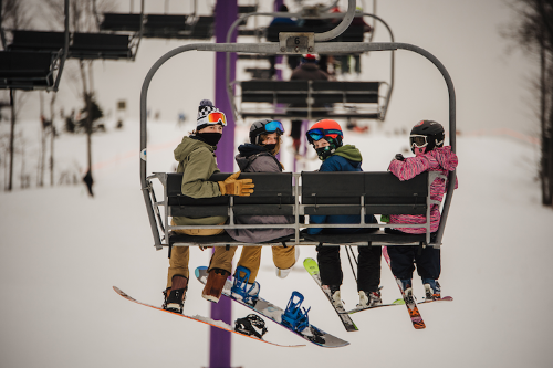Two snowboarders and two skiers on a chairlift. 