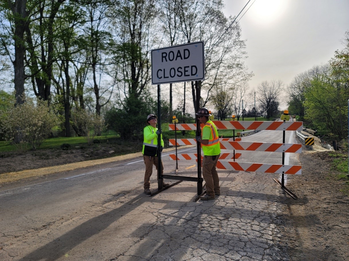 Workers remove barricades at the 33 Mile Road bridge over the east branch of Coon Creek in Macomb County in preparation for reopening to traffic