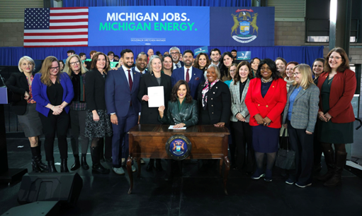 Gov. Whitmer holds signed clean energy legislation surrounded by Michigan legislators and stakeholders.