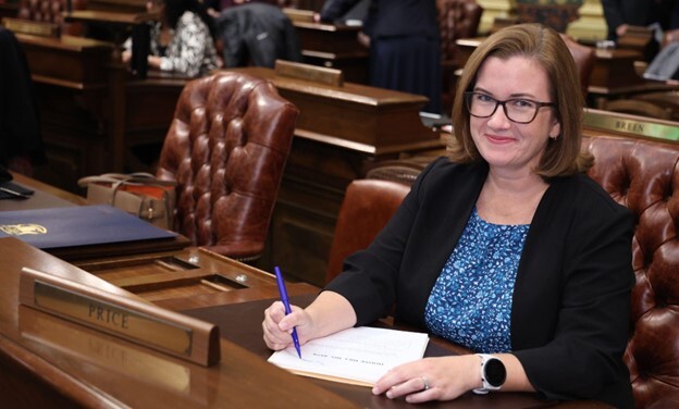 Rep. Price writes on a bill at her desk on the Michigan House floor.