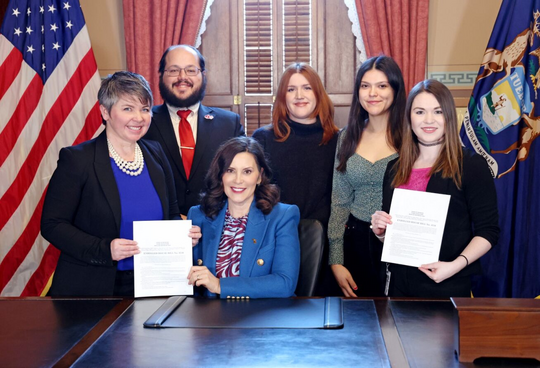 A photo of Rep. Coffia, Governor Whitmer and others at a bill signing ceremony