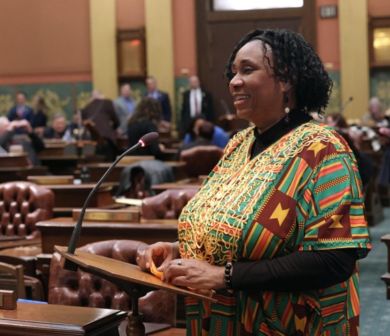 Rep. Steph at the podium on the floor in African-inspired attire for Black History Month, Feb. 2024.