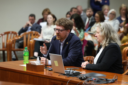 A photo of state Rep. Joey Andrews testifying in committee accompanied by state Rep. Jenn Hill.