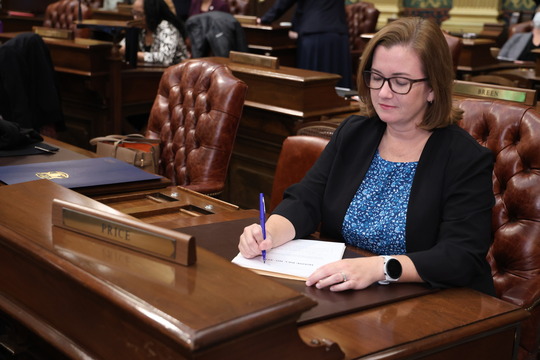 Rep. Price writes on a bill at her desk on the Michigan House floor.