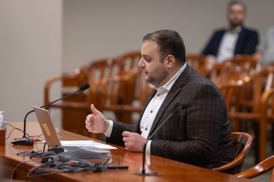 State Rep. Alabas Farhat gestures while reading from a paper at a committee room table.