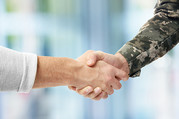 Two hands shaking, one in army fatigues and the other in a suit