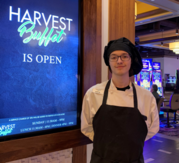 Justin Scripter in chef's uniform in front of restaurant sign