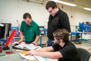 Three men looking at textbooks 