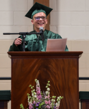 MCTI student standing at a podium in graduation cap and gown