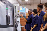 Group of students with instructor working on machine