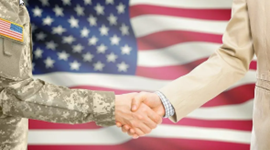 Close up of two people shaking hands with American flag in the background