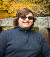 Headshot of Adrian A. standing outside in the fall and wearing sunglasses