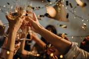 Hands toasting with champagne glasses while confetti falls all around