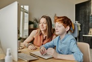 Woman and child sitting next to each other and looking at a computer screen together