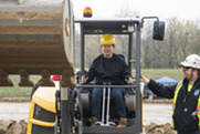 Student operating a construction machine while operator on the side gives instructions