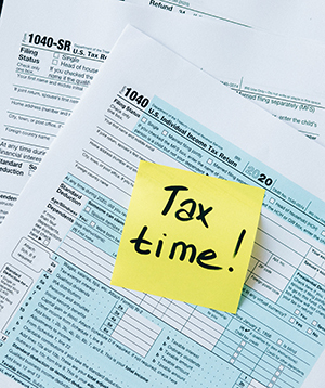 Tax documents with a sticky note on top that says "Tax Time!"