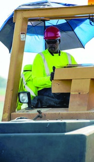 Man in safety gear operating road repair machine