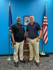 Brett and Jermaine standing in front of U.S. and Michigan flags