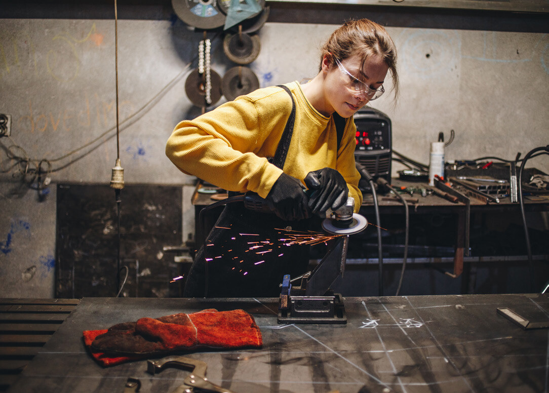 Young woman in a yellow shirt using a power saw