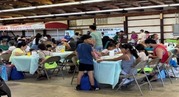 Farmworkers and their families sitting at tables during the Bienvenidos event