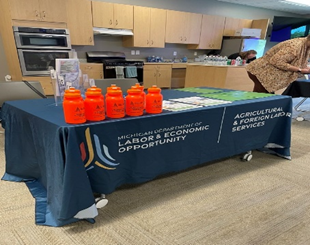 Table with Agricultural and Foreign Labor Services tablecloth and orange water bottles