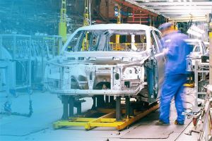 Person in blue coveralls working on the chassis of a car