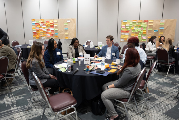 Groups of people at various tables during the Community Growth Academy kickoff event