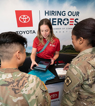 Woman in Toyota shirt speaking with two people in army fatigues