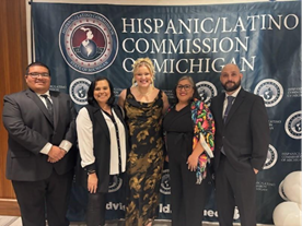 AFLS team standing in front of the Hispanic/Latino Commission sign