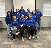 AELs wearing blue shirts and standing and sitting in front of a white screen