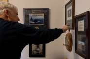 Veteran pointing to awards on his wall