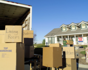 moving truck several boxes on residential street with sold home in background