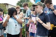 Group of teens holding walking sticks standing outside